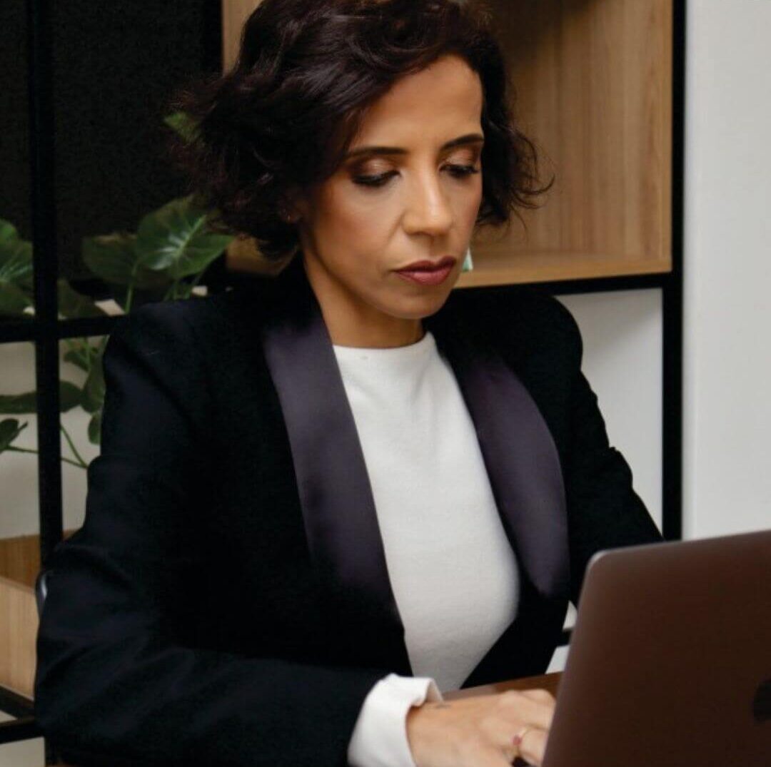 Dra. Fernanda Souza, advogada, concentrada trabalhando em seu laptop, ilustrando o rigor técnico e a análise estratégica aplicada aos casos de Direito da Saúde e Empresarial.